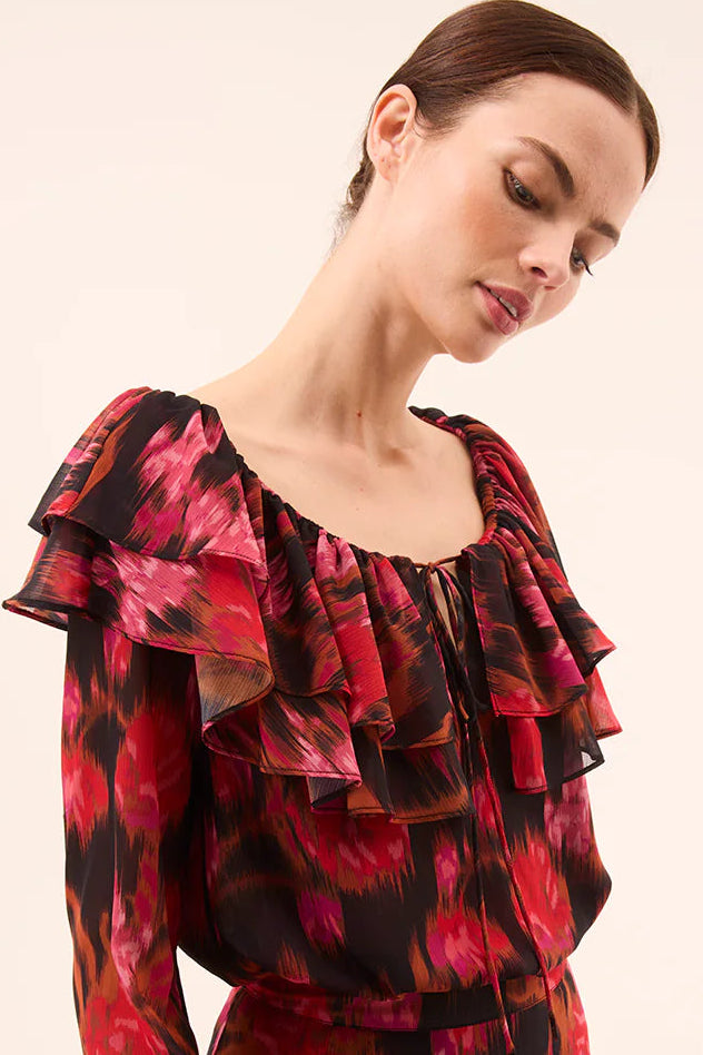 Woman wearing a red and black floral top on a beige background
