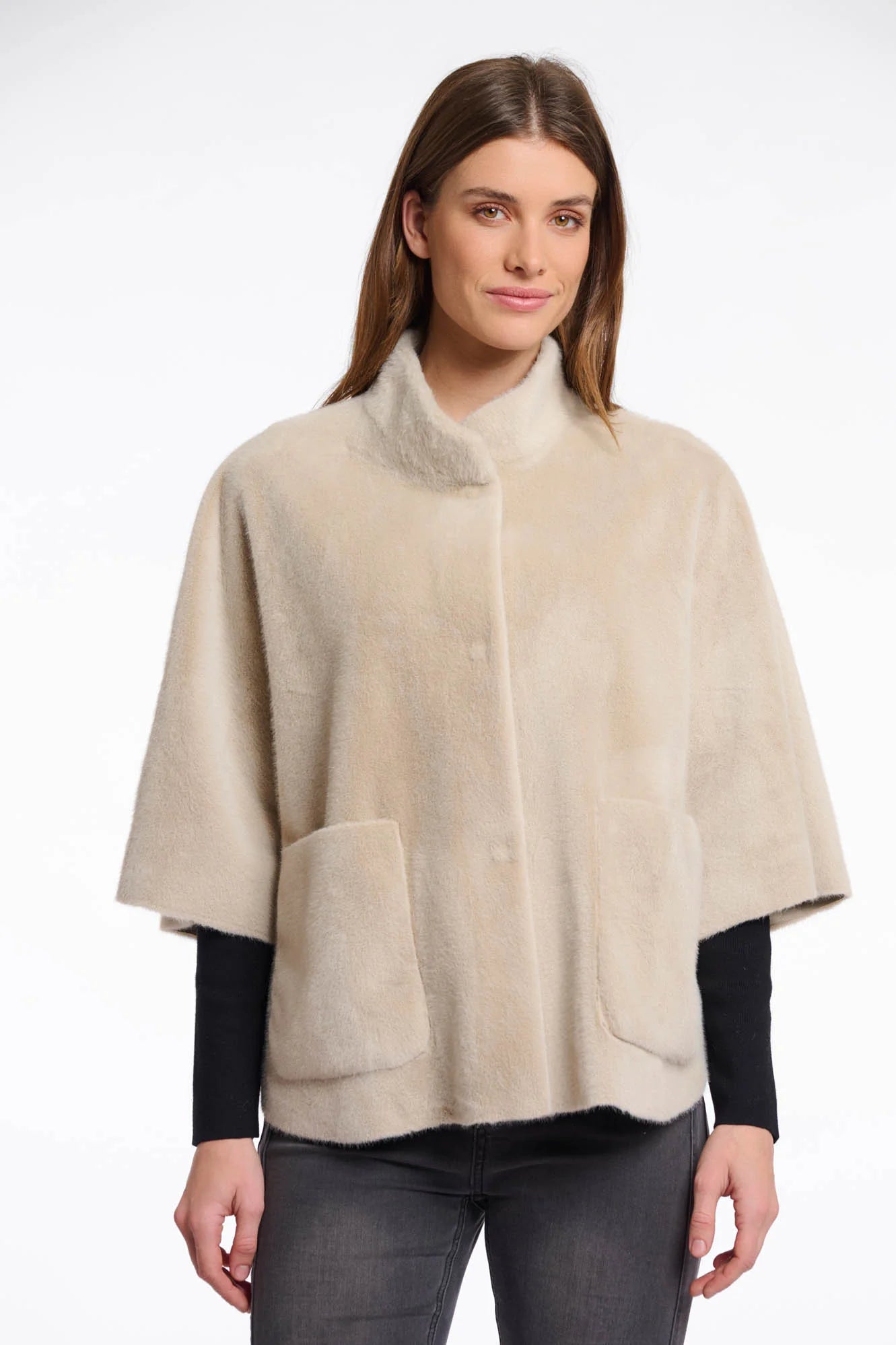Front view of a woman wearing a beige cape over a black top and pants
