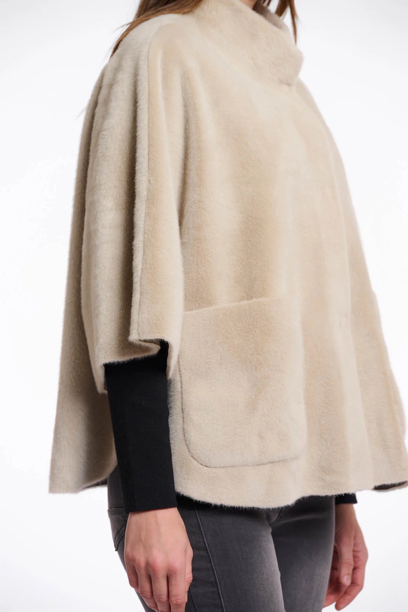 Close-up  view of a woman wearing a beige cape over a black top and pants