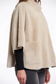 Close-up  view of a woman wearing a beige cape over a black top and pants