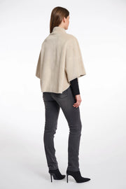 Back  view of a woman wearing a beige cape over a black top and pants