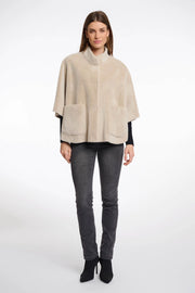 Full body  view of a woman wearing a beige cape over a black top and pants
