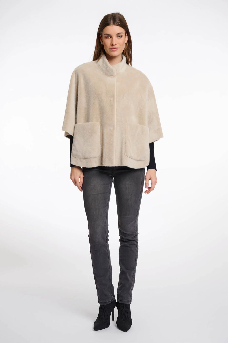 Full body  view of a woman wearing a beige cape over a black top and pants
