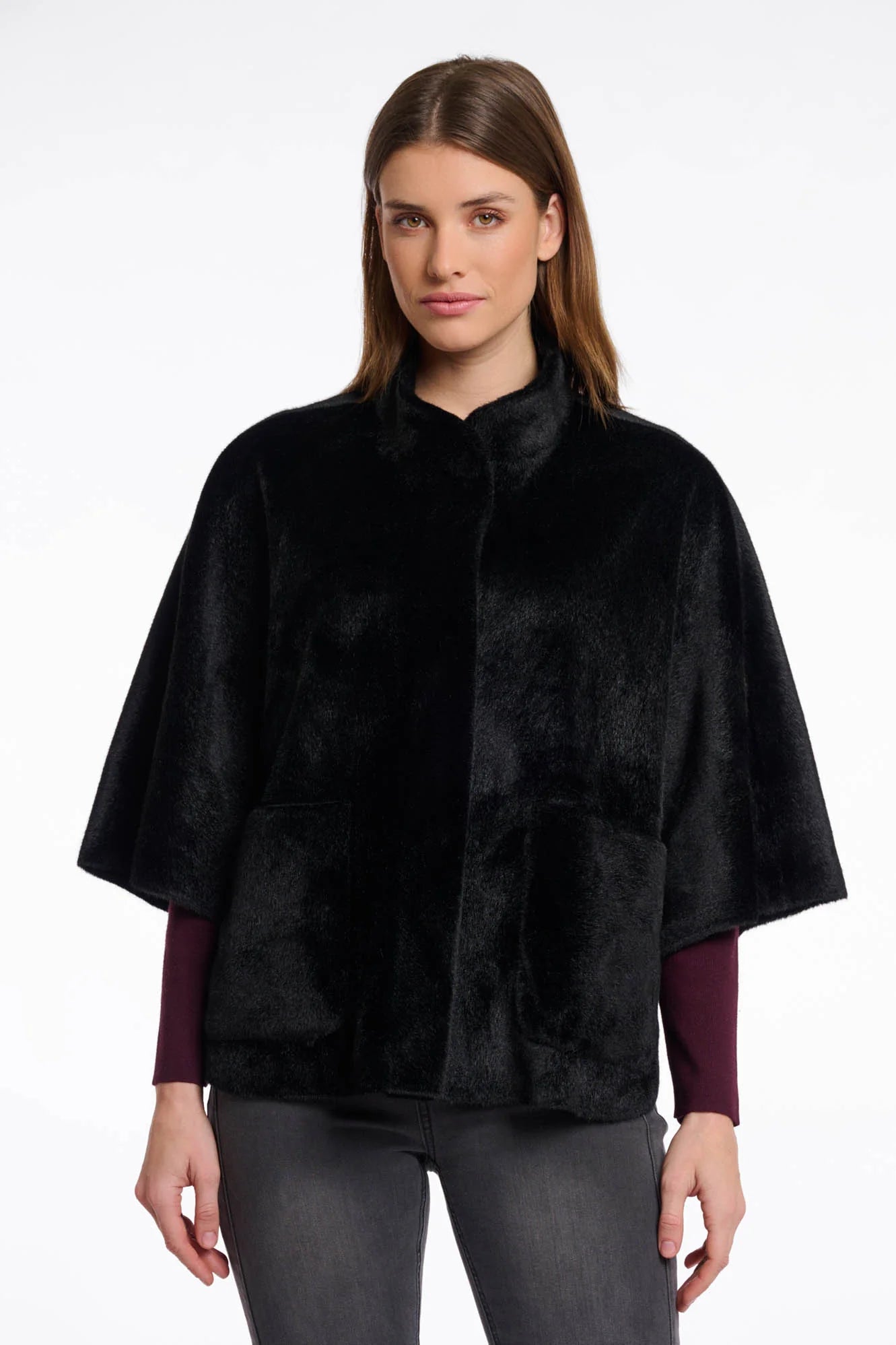 Front view of a woman wearing a black fur cape over a dark outfit on a white background