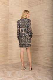 Back view of woman wearing a black, green and beige patterned cuffed long sleeve short dress
