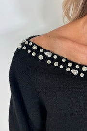 zoom in view of woman wearing a black sweater with rhinestones in the neckline