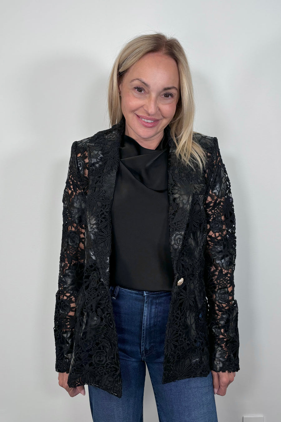 Front view of woman wearing a satin sleeveless top with a vegan leather lace blazer