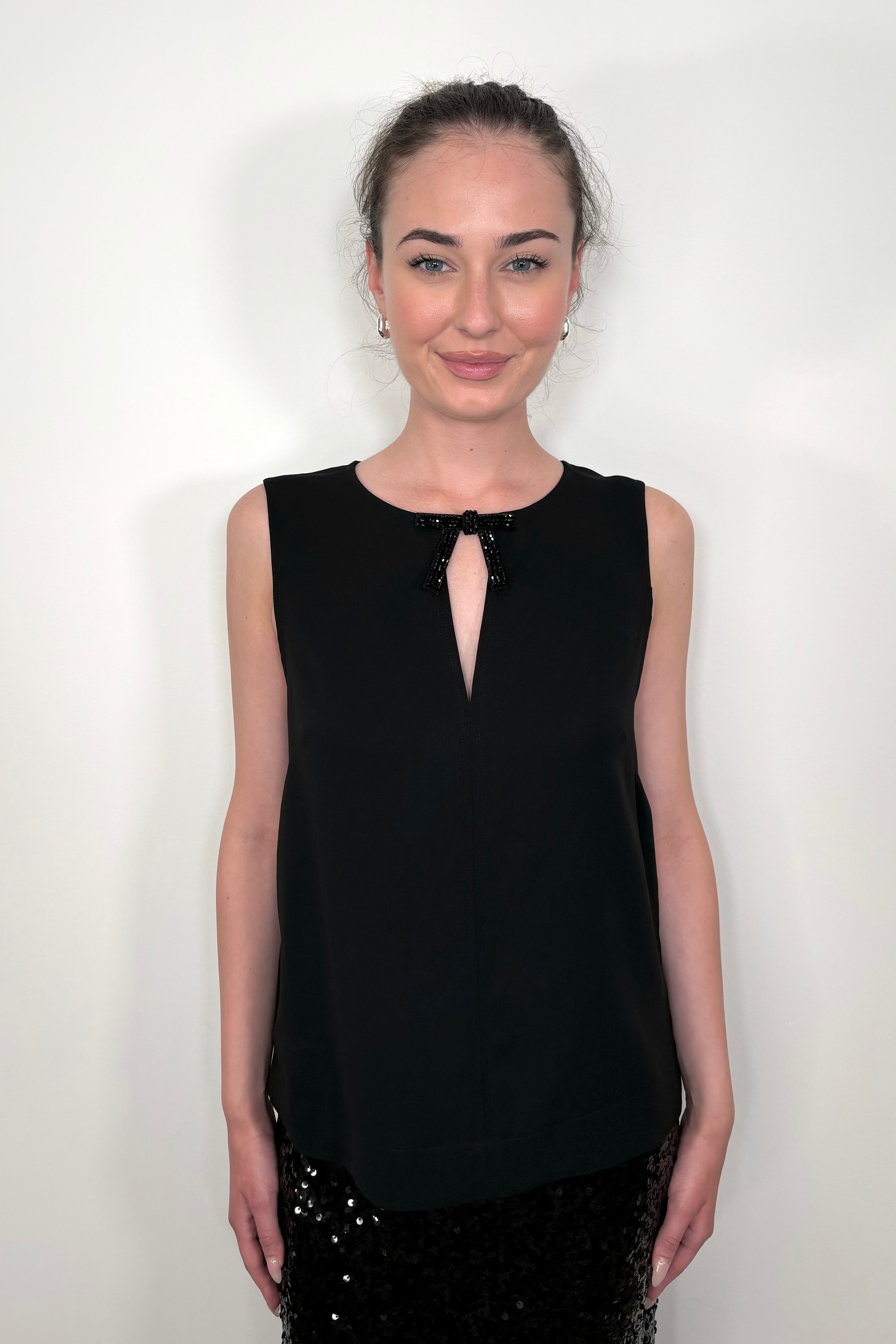 woman wearing a black tank top with crystal bow detailing