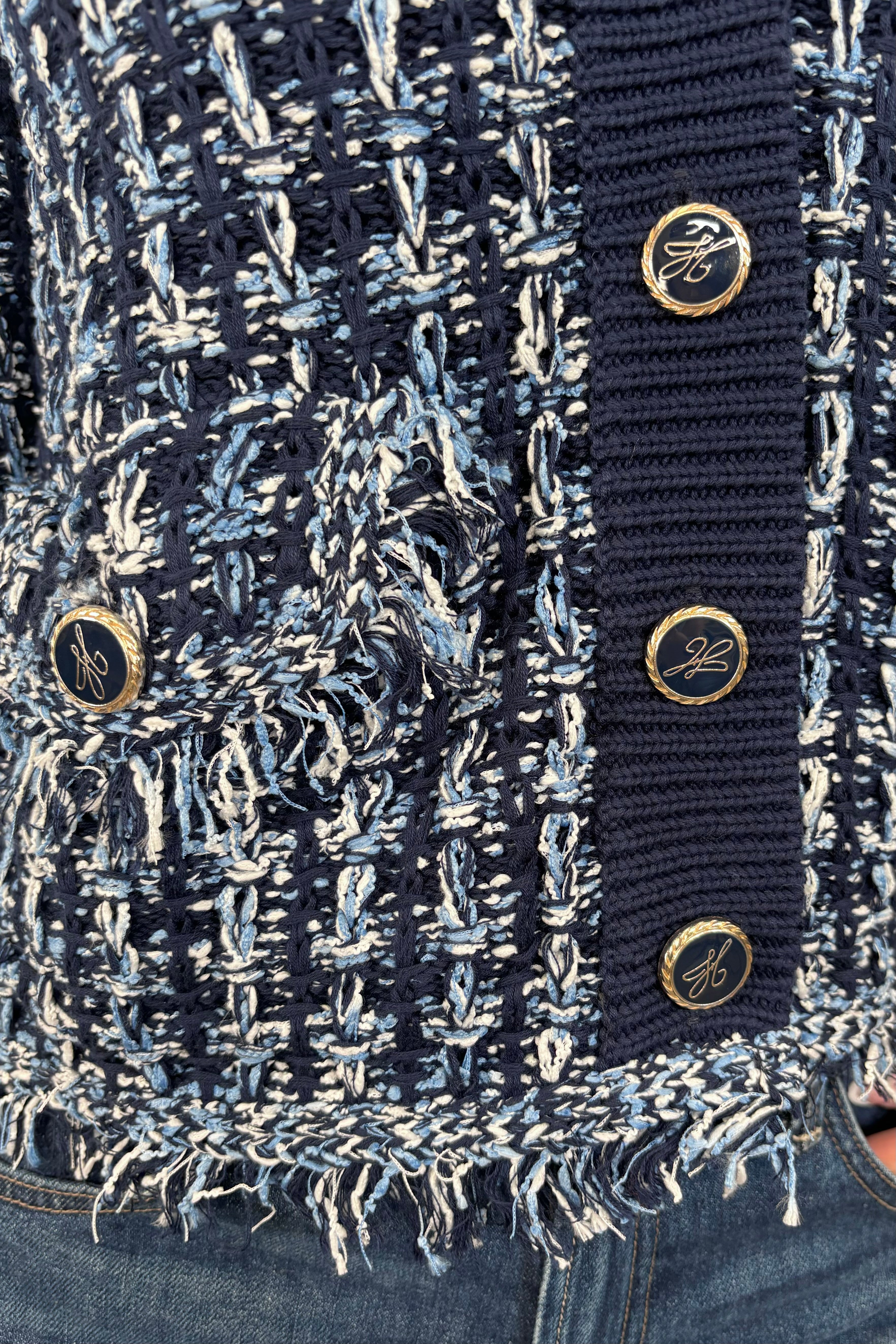 Close up view of woman wearing a knit blue jacket with ornamental buttons
