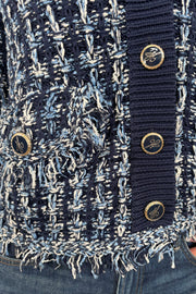 Close up view of woman wearing a knit blue jacket with ornamental buttons