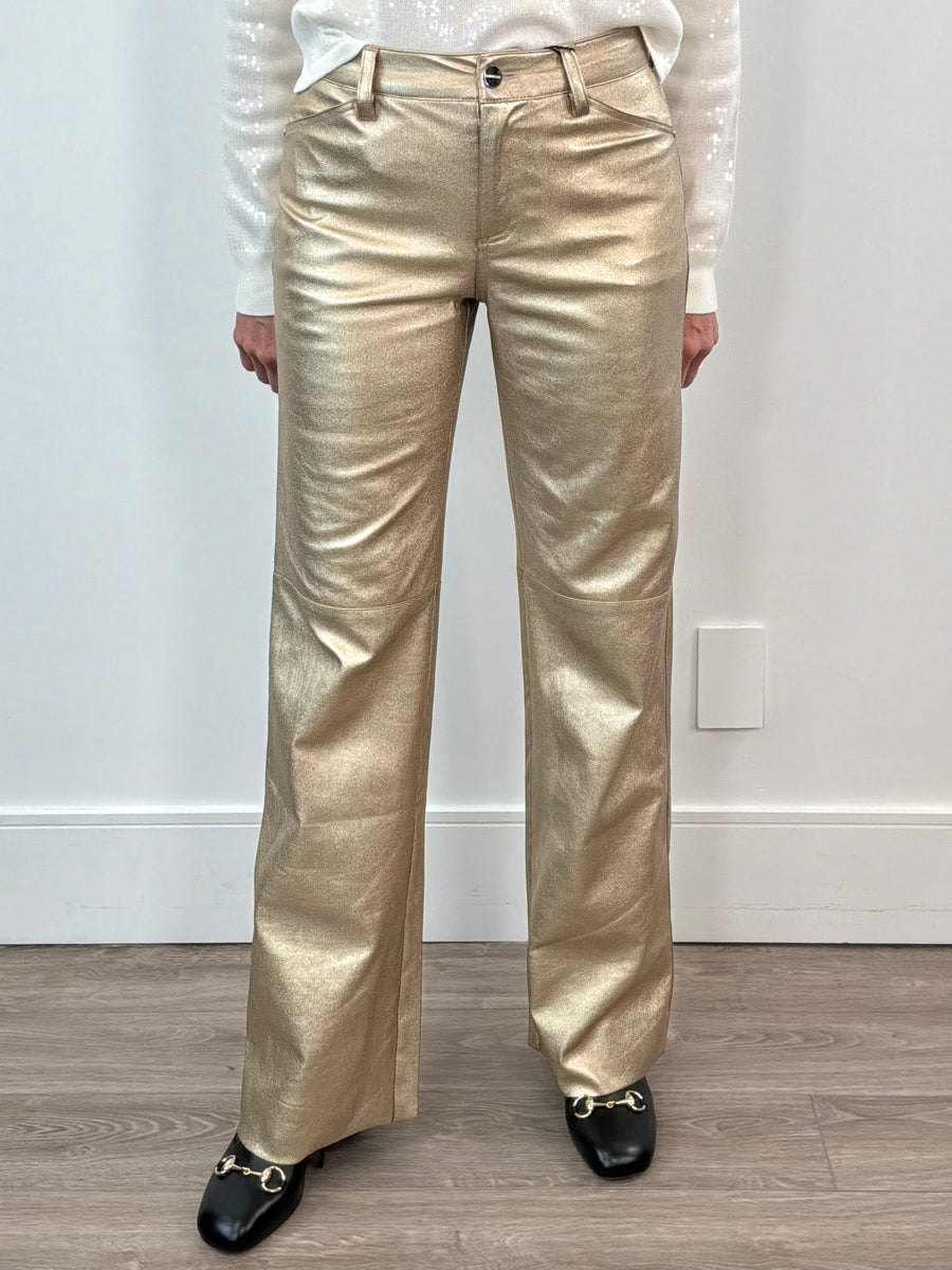 Person wearing gold metallic pants against a white wall.