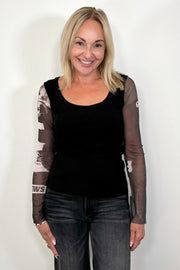 Front view of woman wearing a black torso mesh-long sleeve top with prints on the sleeves