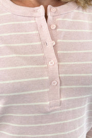 Close up of Woman wearing a long sleeved pink henley knit top with cream stripes and a button placket