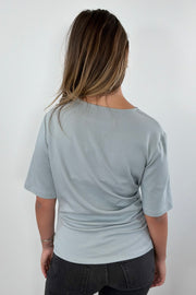 Woman wearing a blue gray t-shirt with twist detail