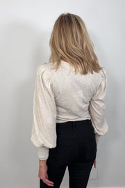 Back view of a woman wearing a blouson cuffed sleeve beige top