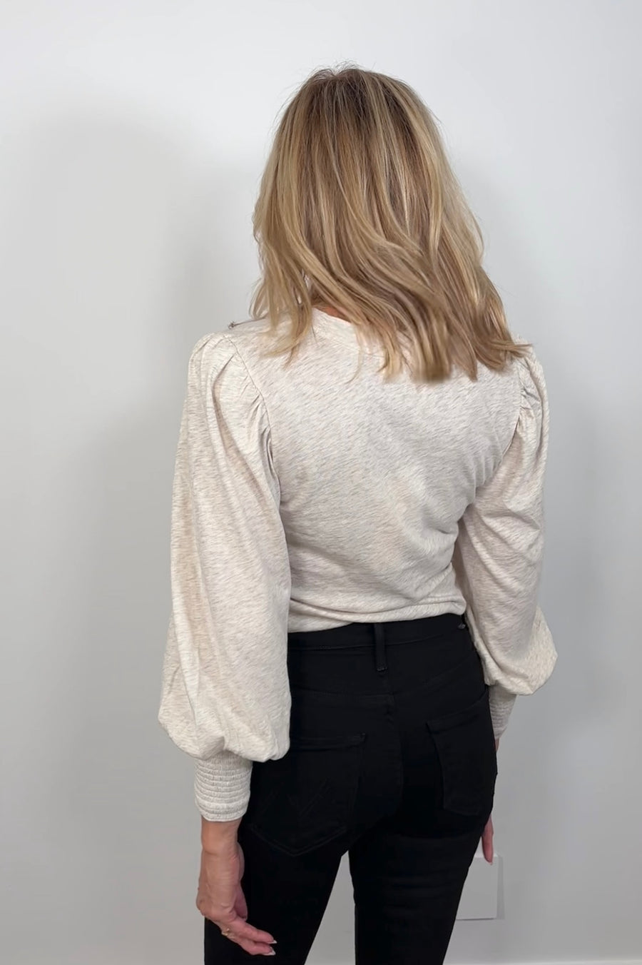 Back view of a woman wearing a blouson cuffed sleeve beige top