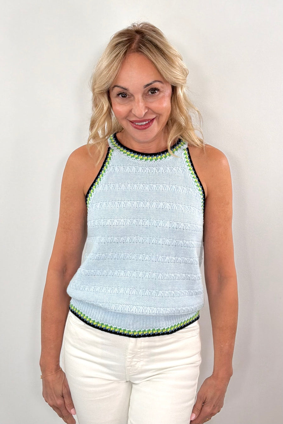 woman wearing a light blue knitted tank with black and green stitching