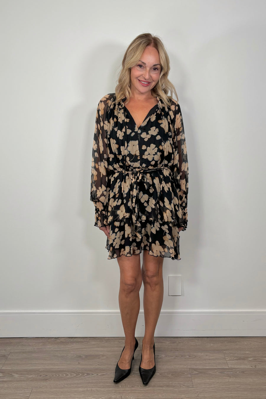 woman wearing a mini black with beige flowers dress with long sleeves