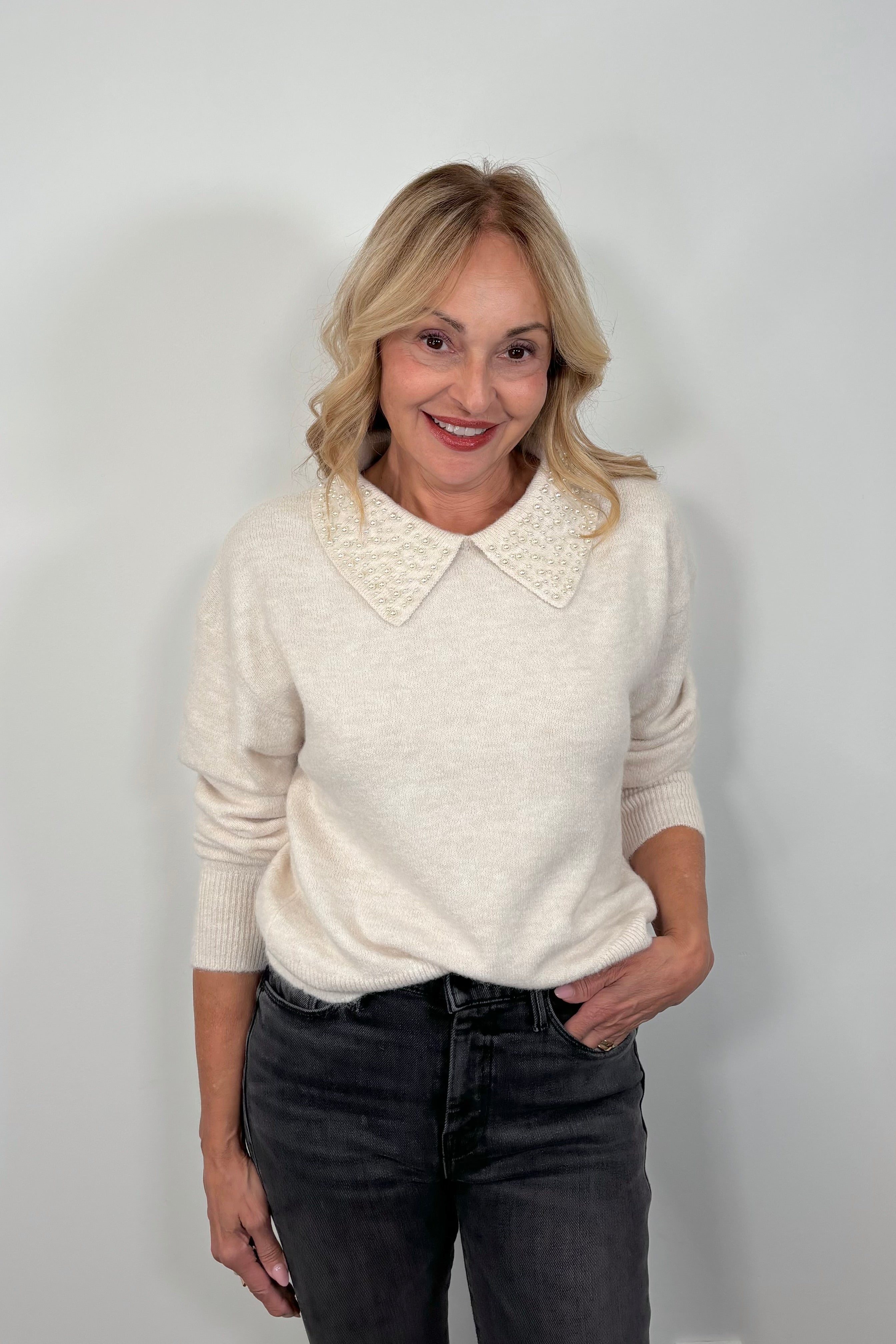 woman wearing an off white collard sweater with pearl detailing 