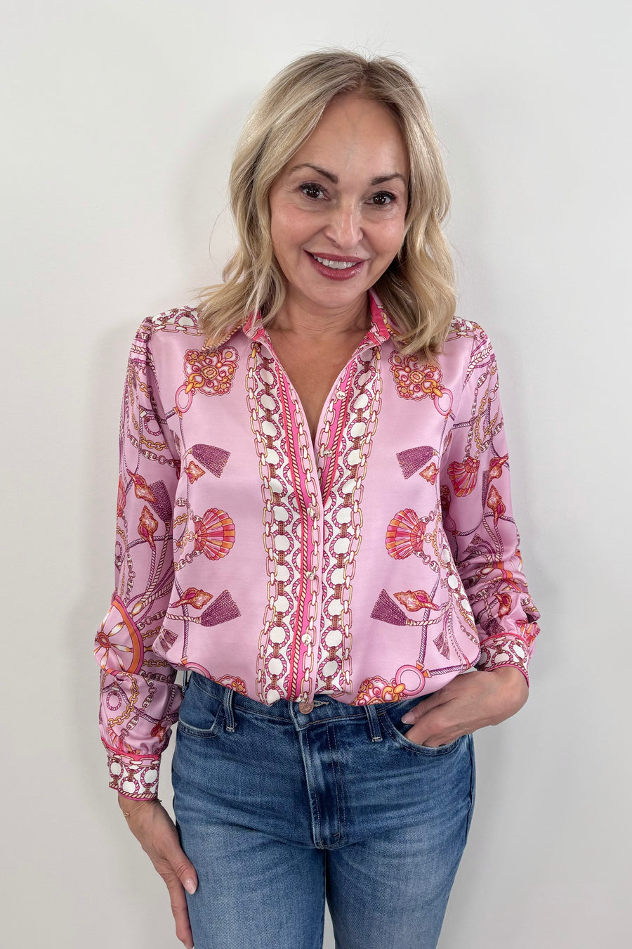 woman wearing a pink silk button down with rouching on the sleeves tucked in