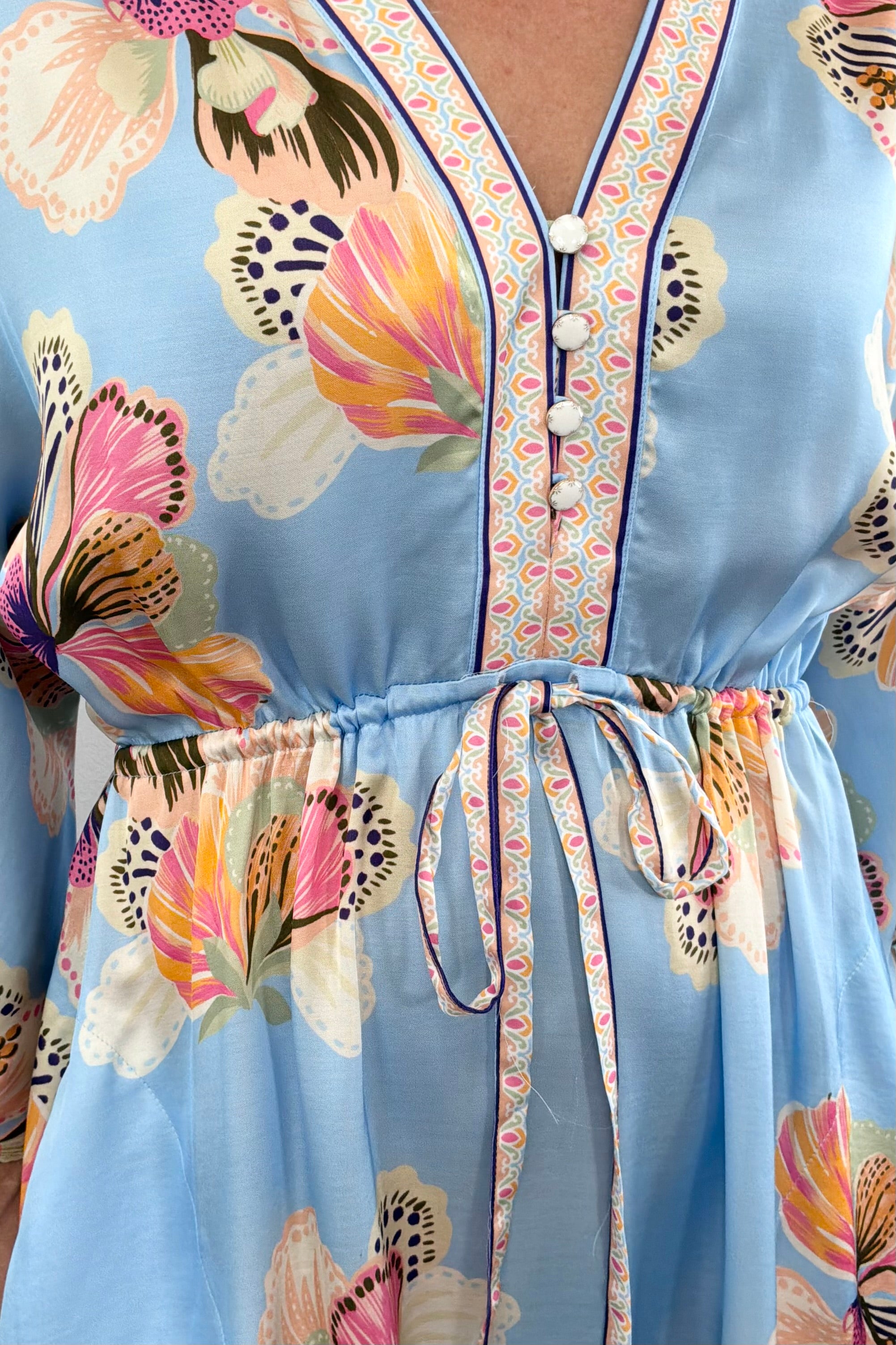 Woman wearing a light blue floral kimono dress with tie around the waist 