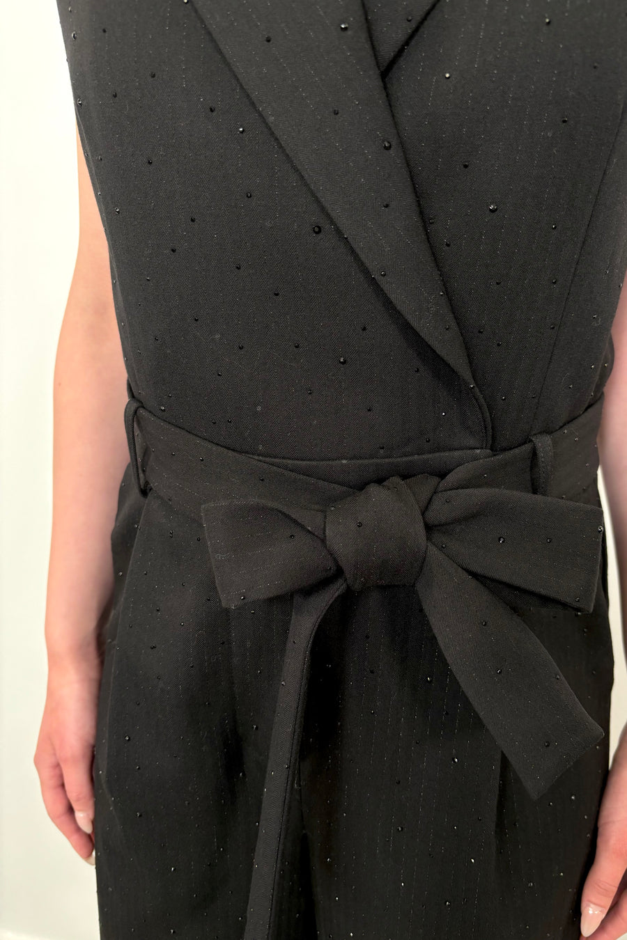 Close up of a woman’s waist wearing a black pinstriped jumpsuit with sparkle embelishment