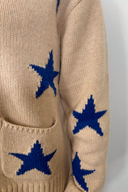 Close-up of a beige zip-up sweater with blue star patterns and front pockets