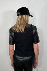 Back view of woman wearing a black mix leather and crochet tee