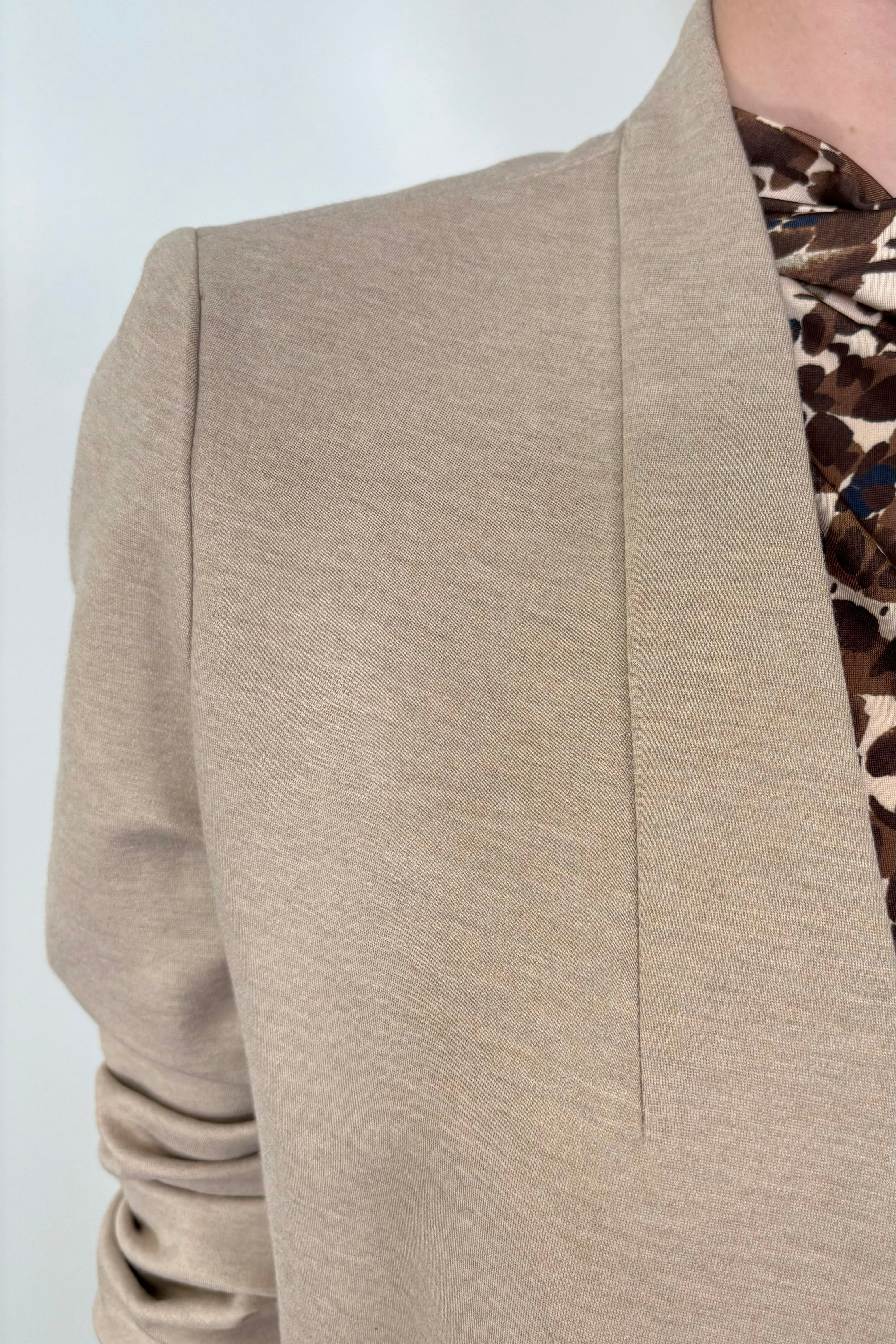 Close up of woman using a beige neutral stretch collarless ponte blazer