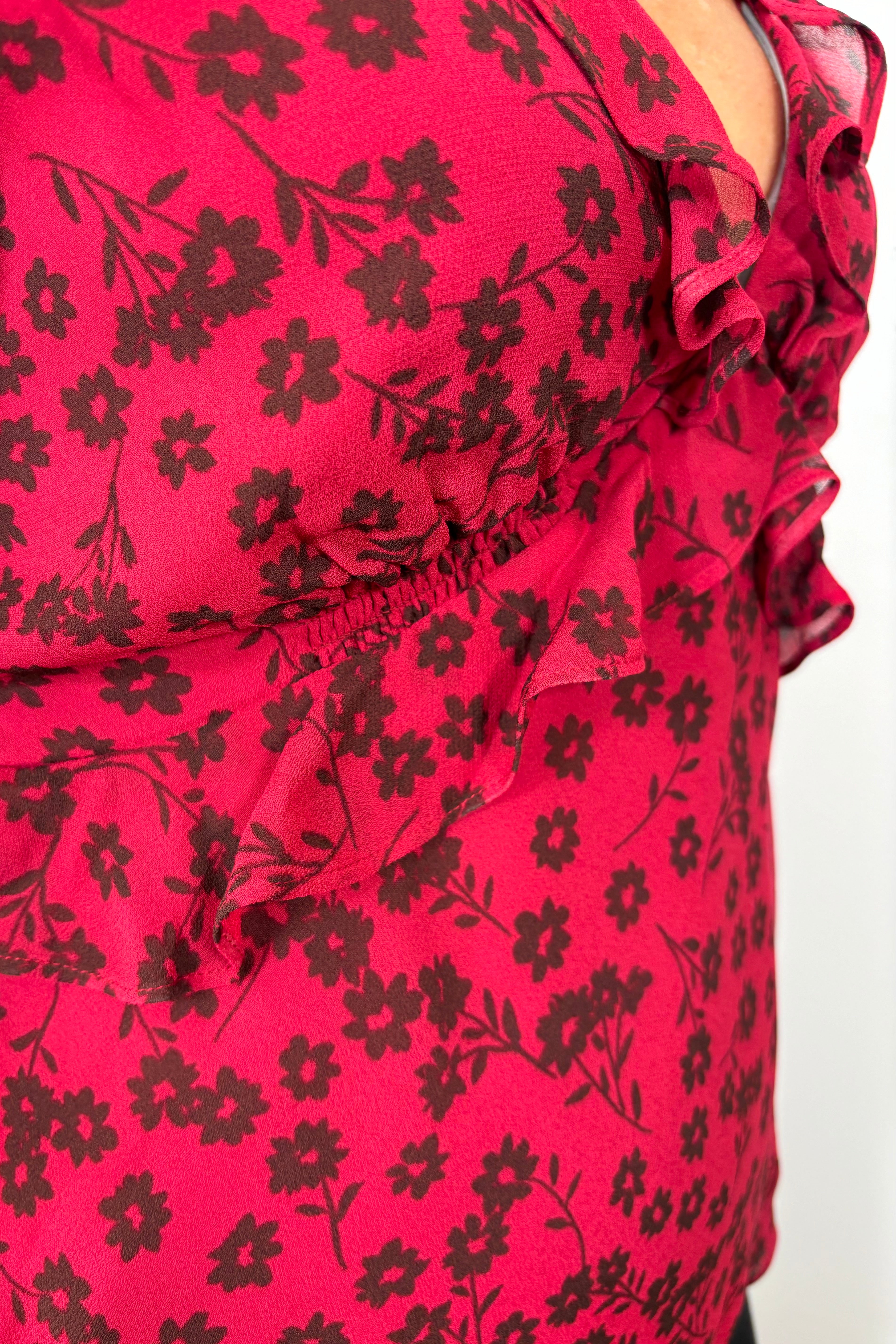 Close-up view of woman wearing a cool red chiffon top with a daisy pattern