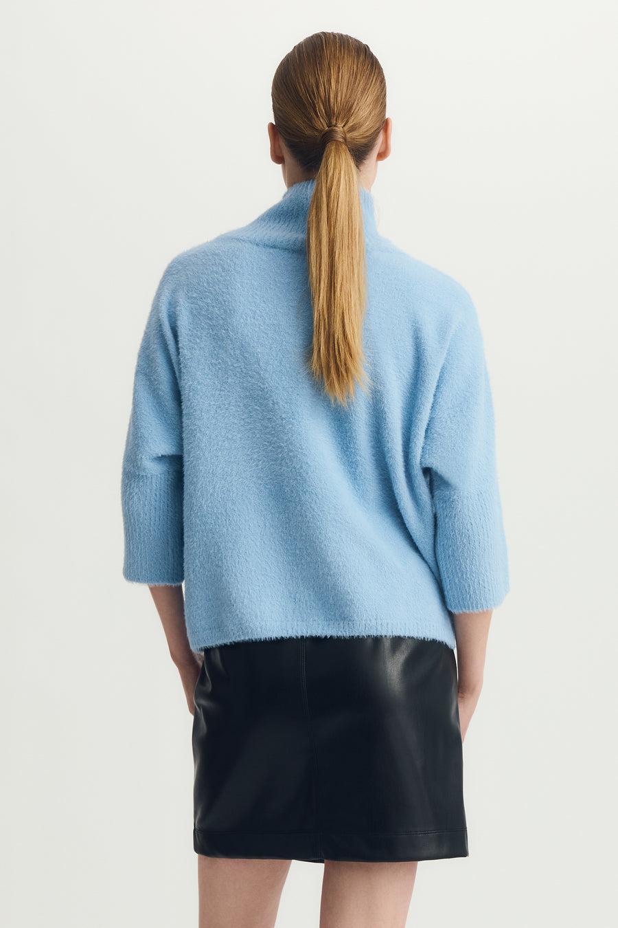 Back view of a woman wearing a half sleeve mock neck hairy blue sweater