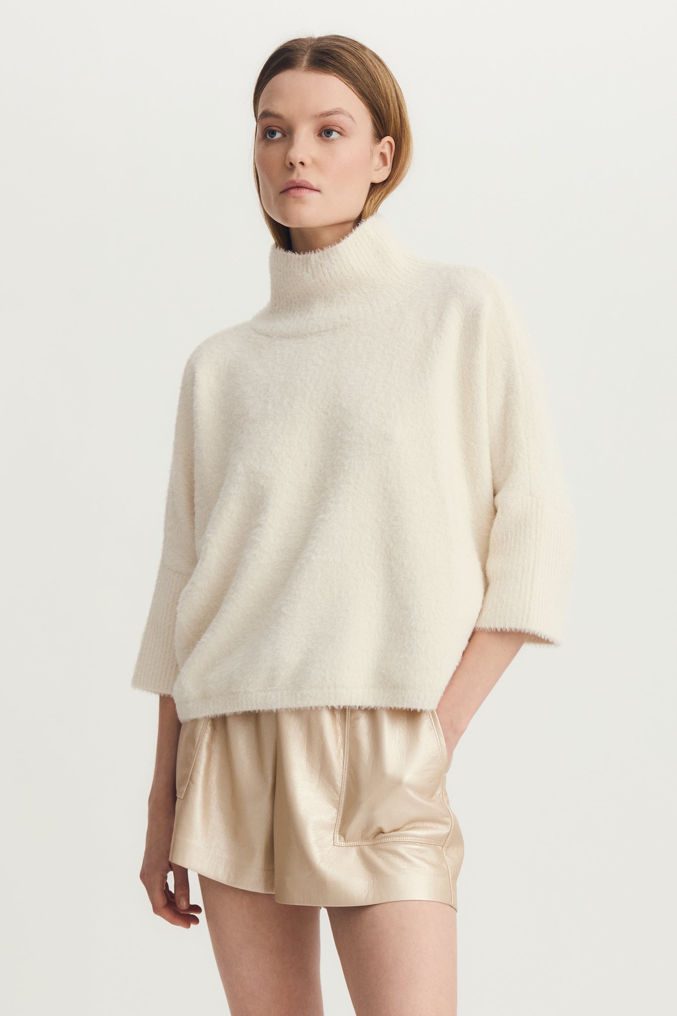 Front view of woman wearing a mock neck half sleeve hairy cream sweater
