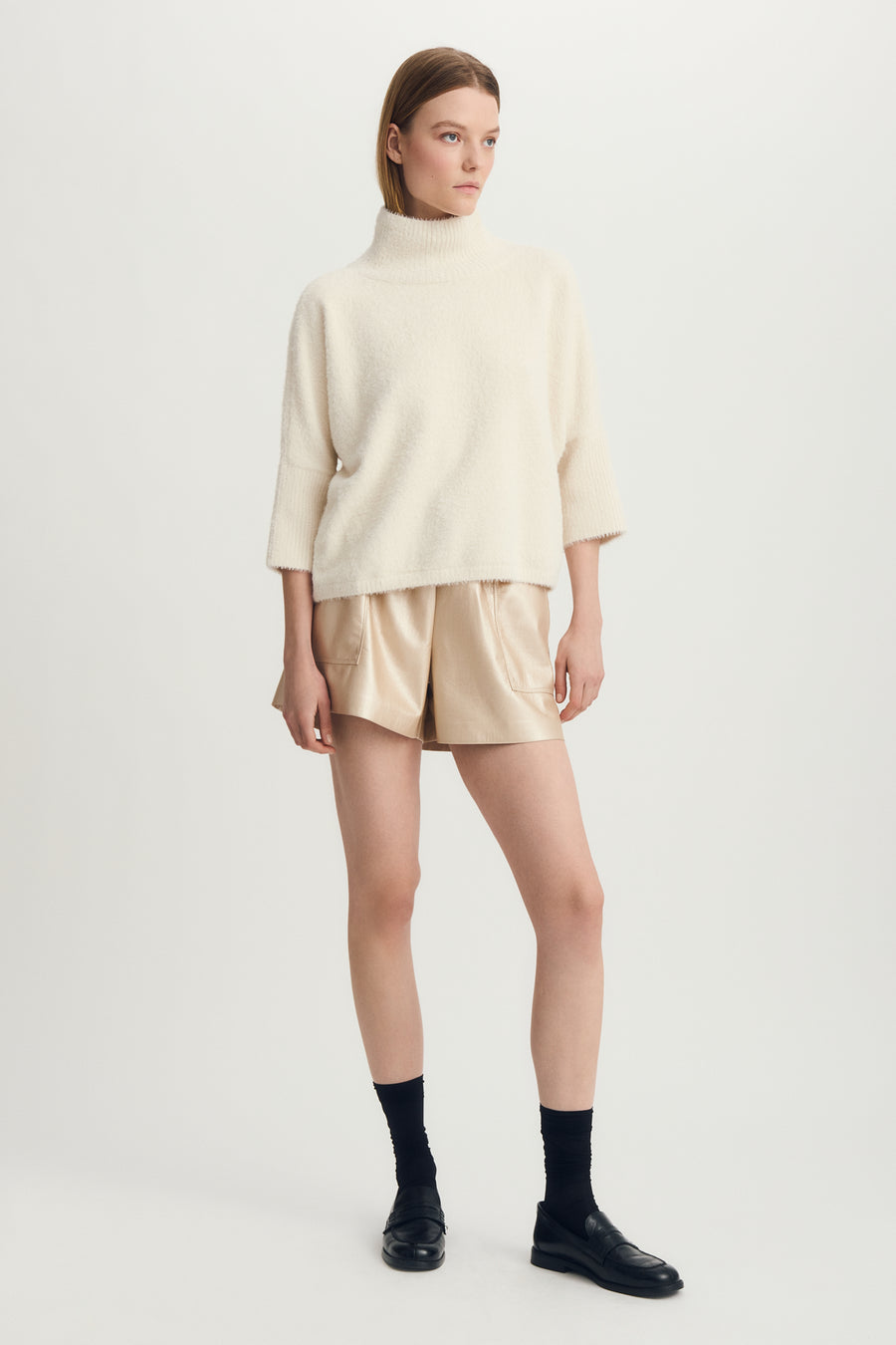 Front  full body view of woman wearing a mock neck half sleeve hairy cream sweater