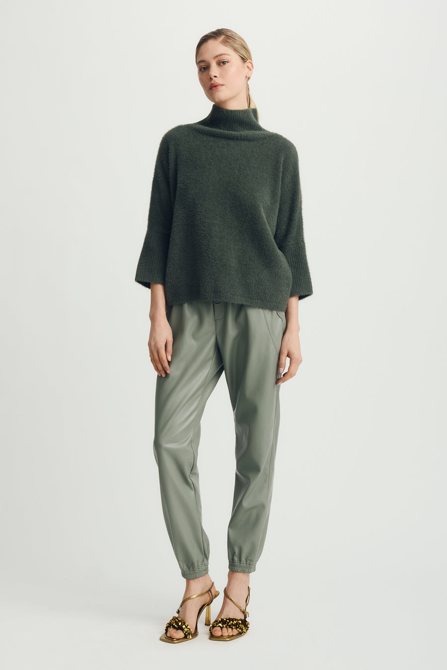 Full body view of a woman wearing a green half sleeve hairy sweater