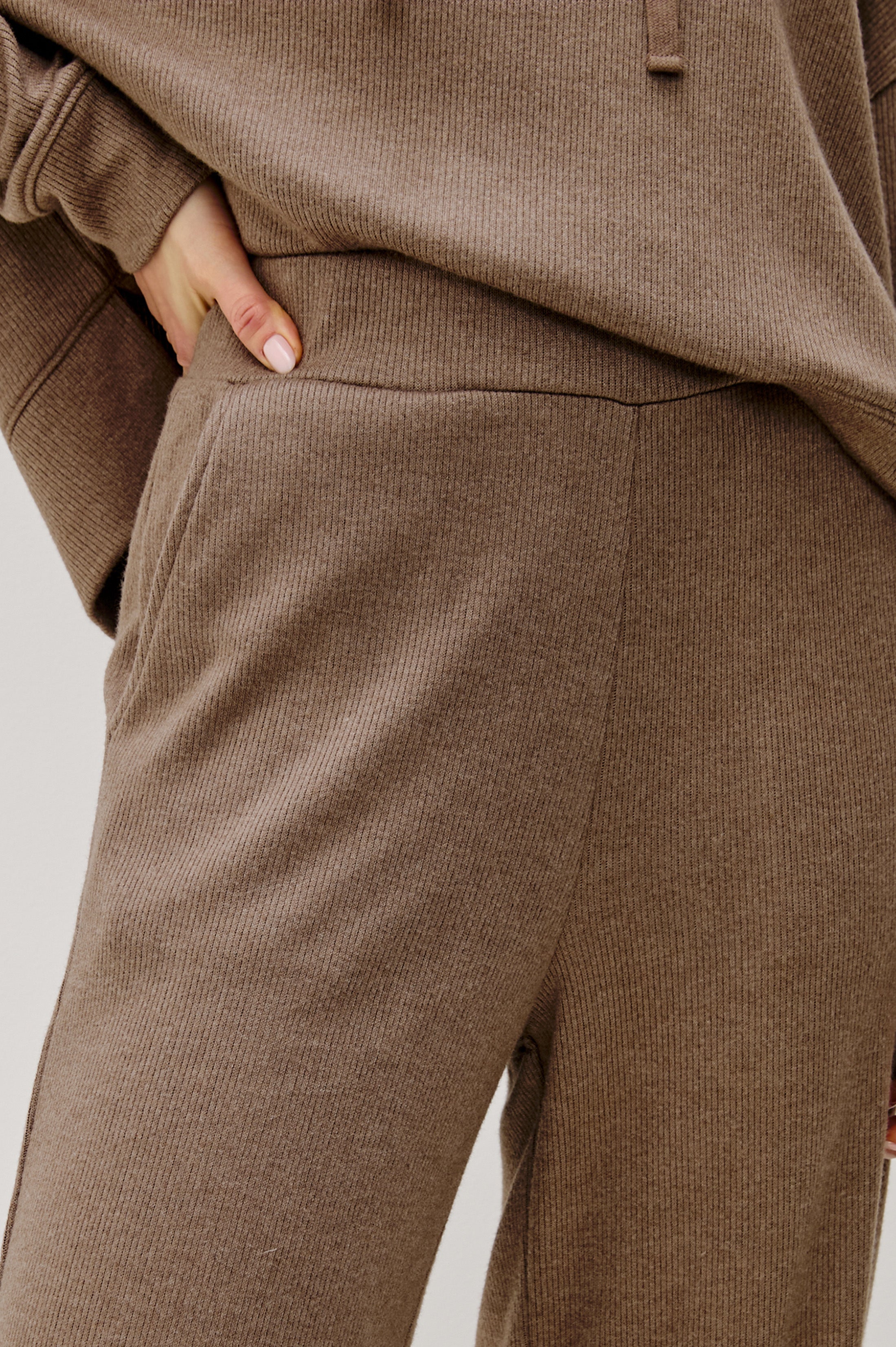 close up view of a person wearing brown pants on a white background 