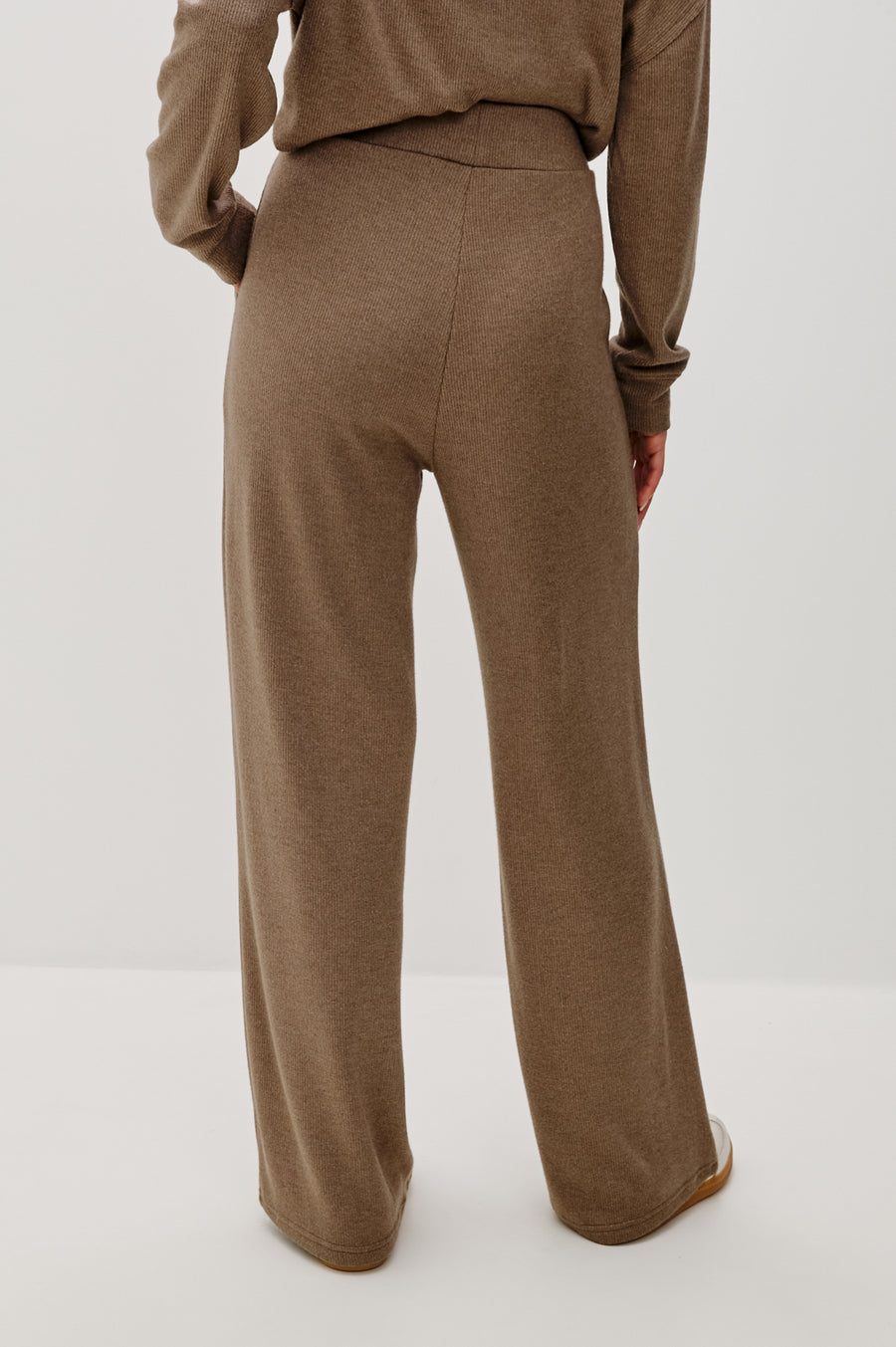 Back view of a person wearing brown pants on a white background 