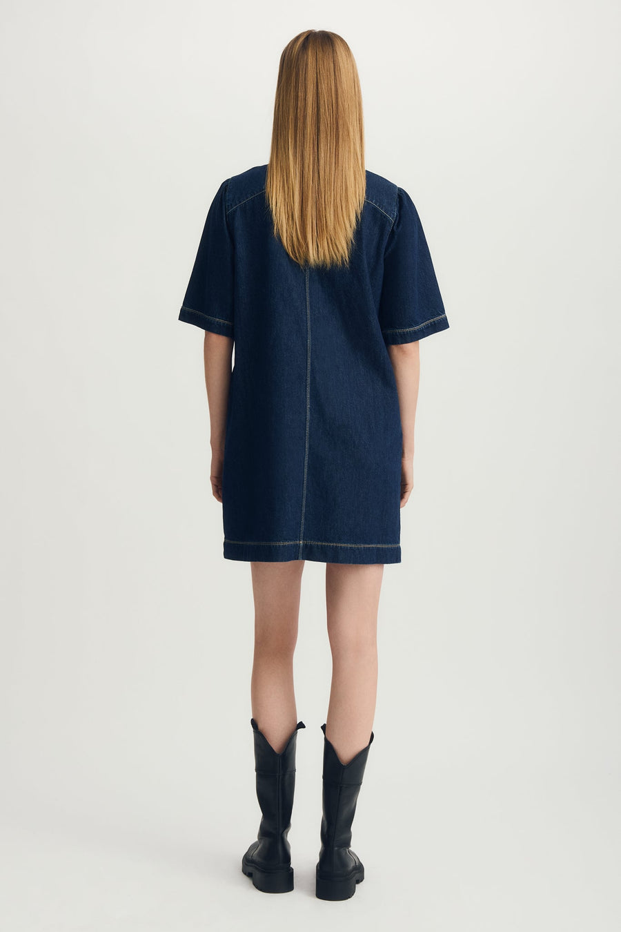 Person wearing a blue denim dress on a white background