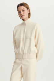Woman wearing a cream mix media bomber jacket with front pockets