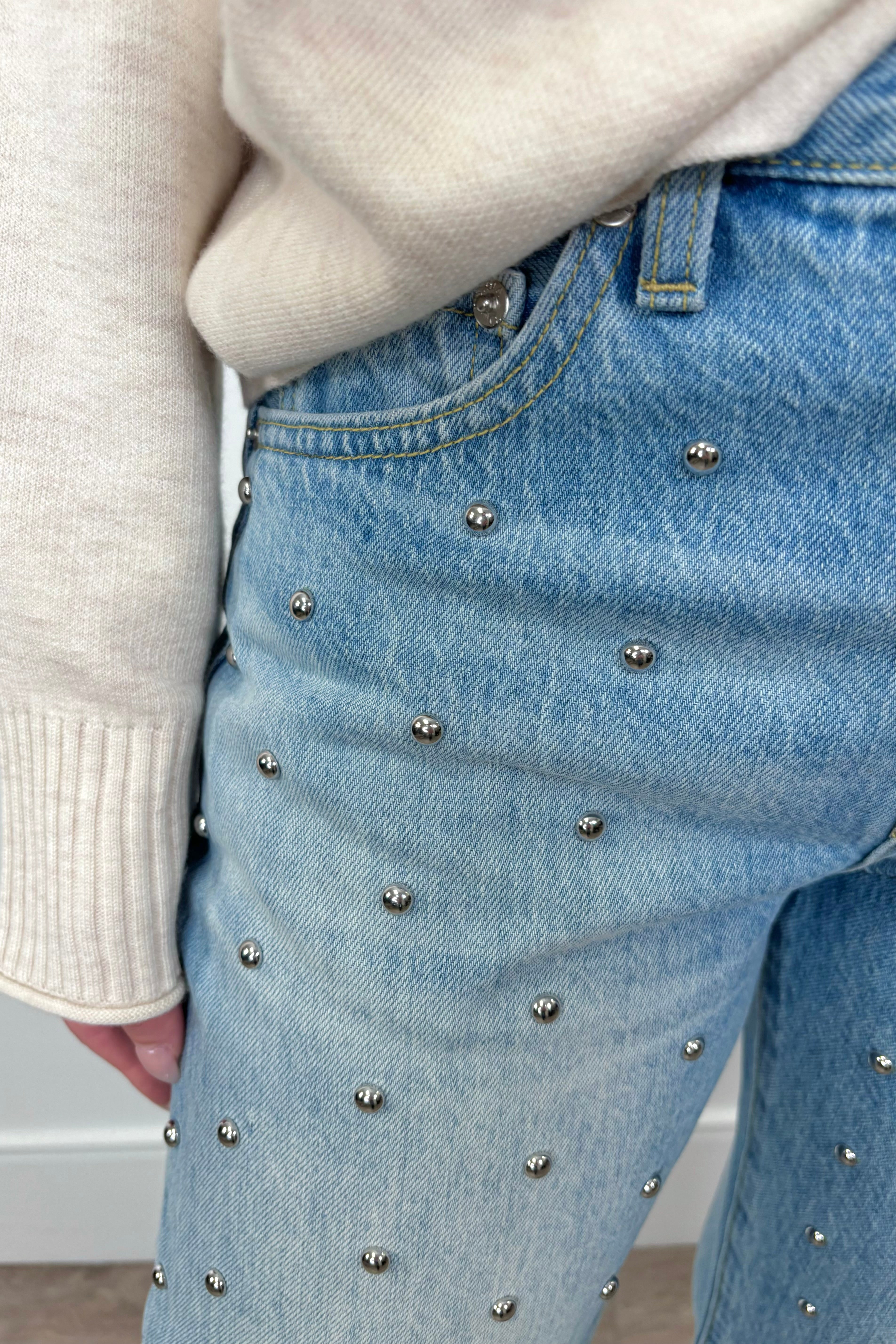 Close up view of woman wearing blue denim jeans with silver studs