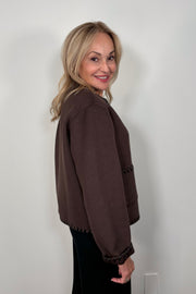 Side view of woman wearing a buttoned up brown wool with whipstitch detailing