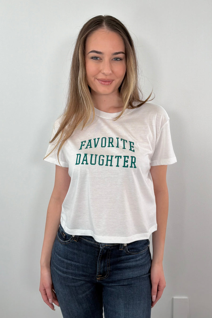 woman wearing a white t-shirt with 'Favorite Daughter' text 