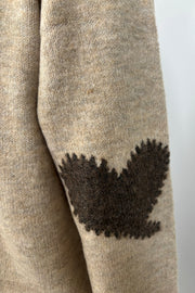 zoom in view of the heart detail on the elbow of a beige cardigan