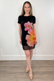 Woman wearing a black dress with a mesh dress on top that has a floral design