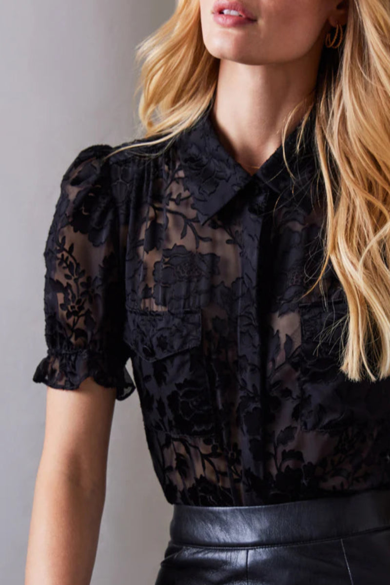 Black lace blouse worn by a person against a neutral background