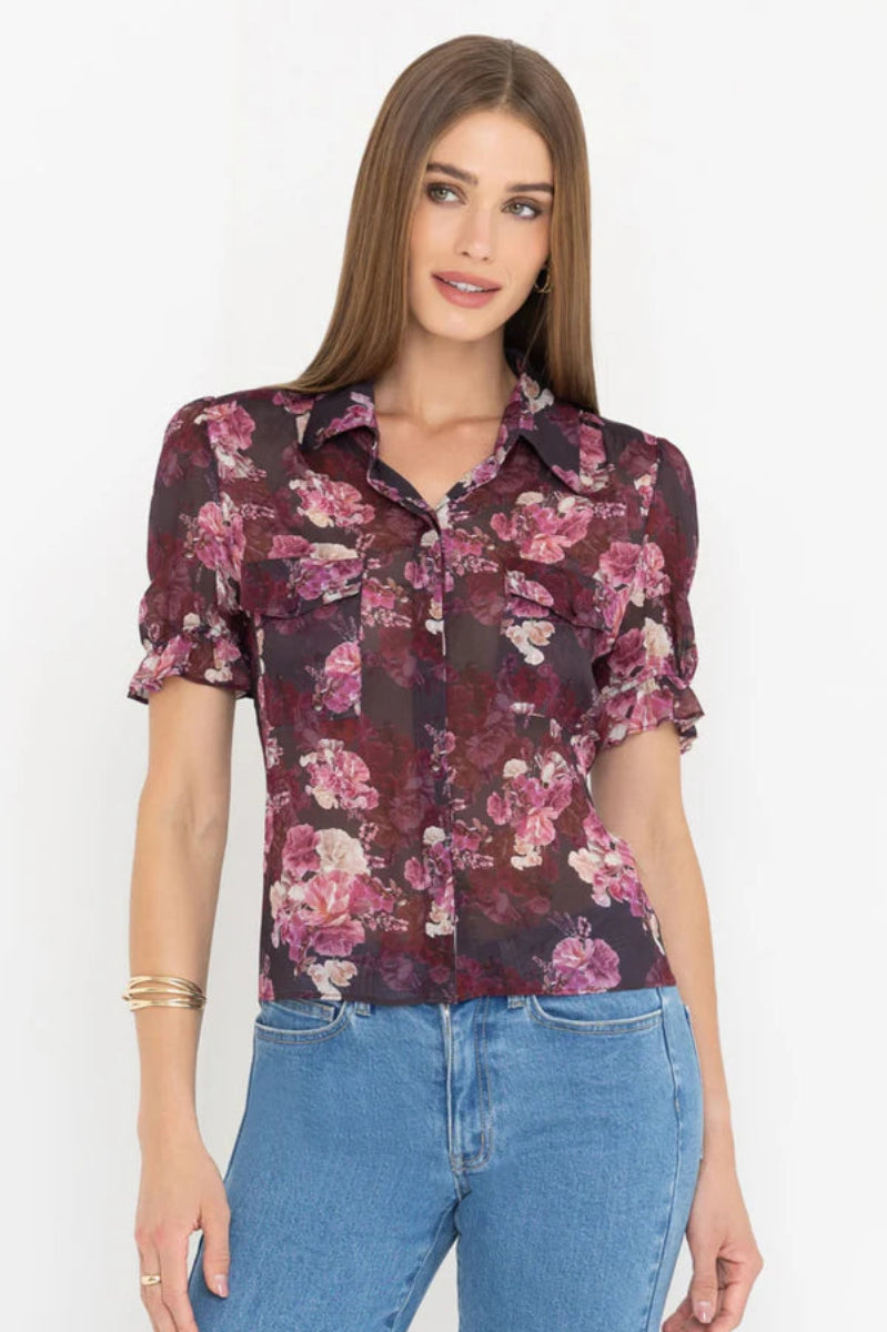 Front view of woman wearing a black and pink floral blouse and jeans on a white background