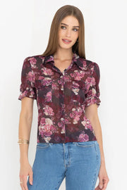 Front view of woman wearing a black and pink floral blouse and jeans on a white background