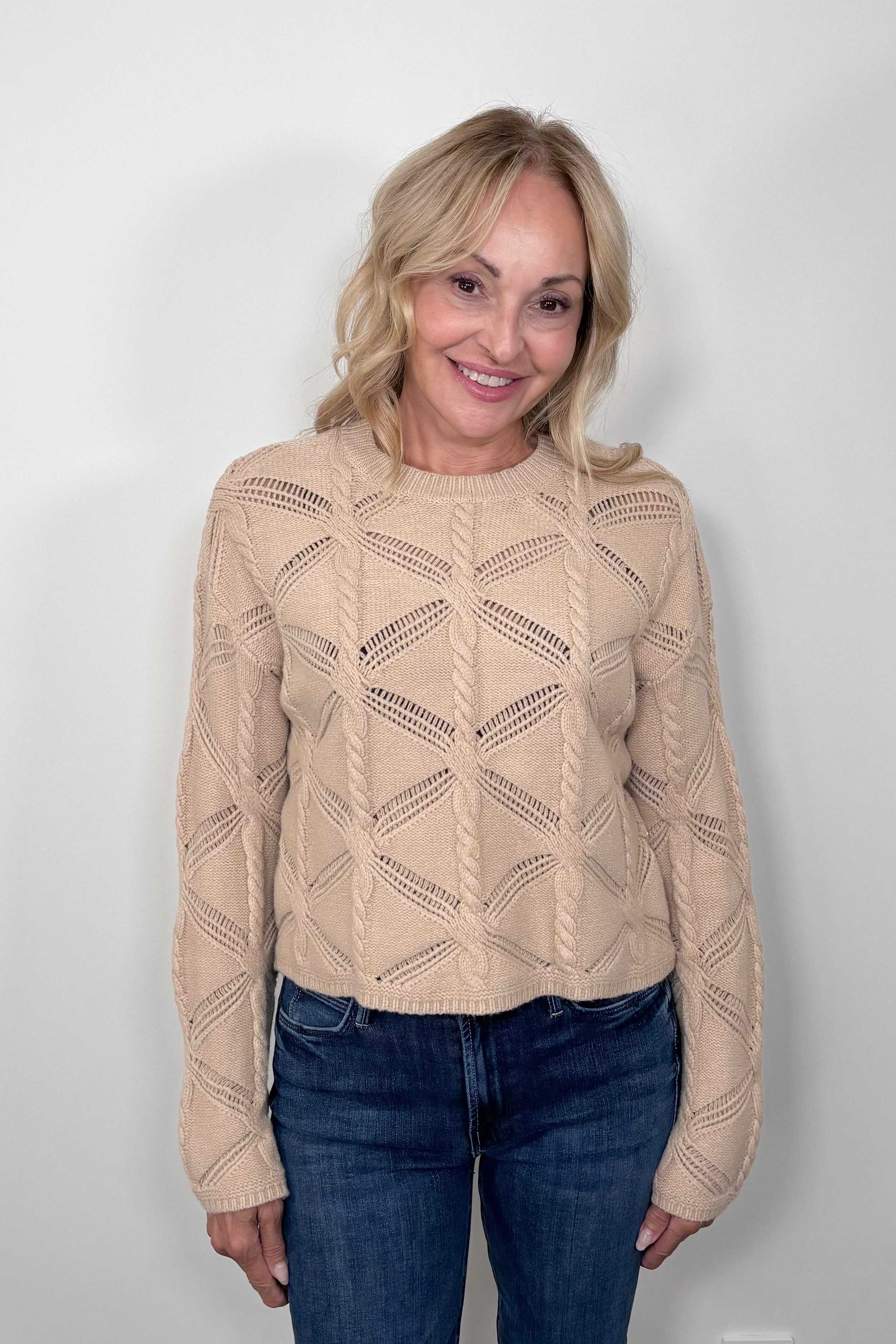 Front view of a woman wearing a camel cable knit sweater