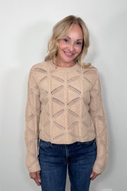 Front view of a woman wearing a camel cable knit sweater