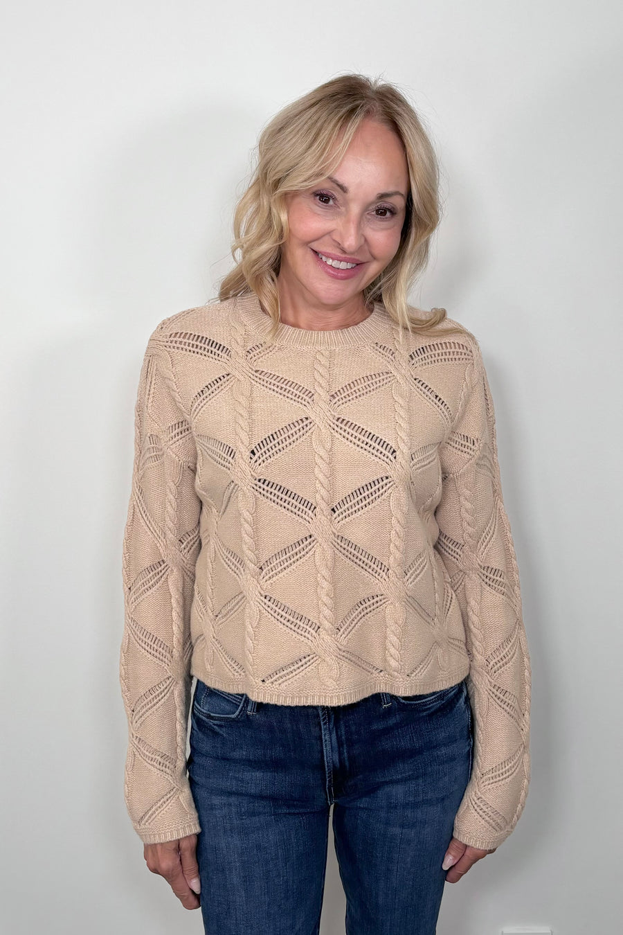 Front view of a woman wearing a camel cable knit sweater