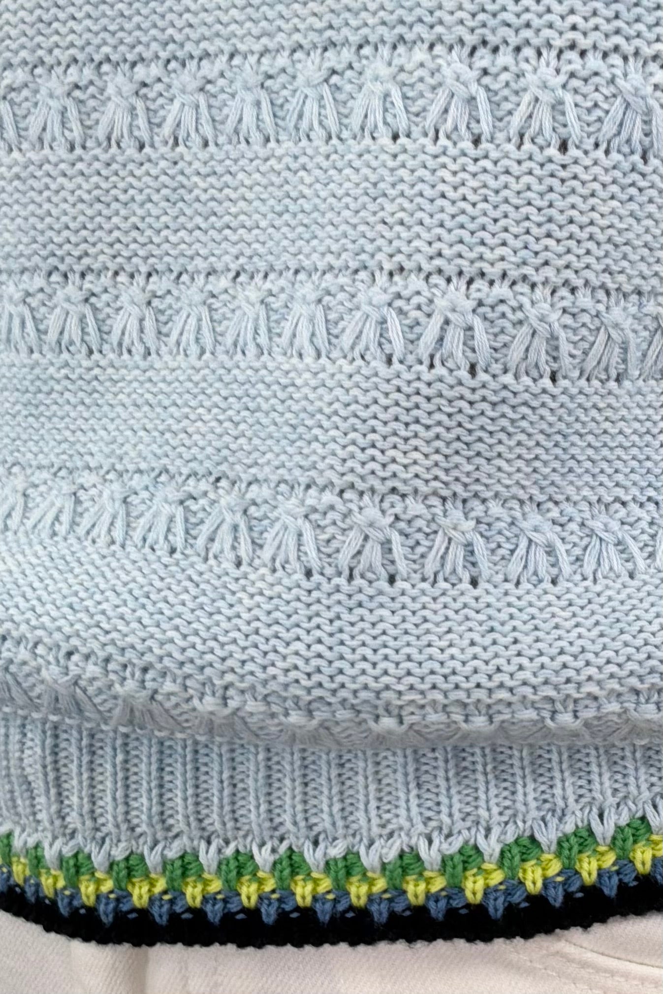 Close-up of a light blue knitted tank with black and green stitching